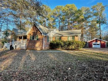 Charming brick home with a covered porch and a detached garage nestled among mature trees at 342 Mccurry Rd, Stockbridge, GA 30281