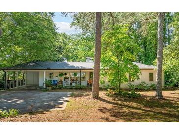 Charming single-story home with a white facade, covered porch and lush landscaping at 3294 Mcclure Bridge Rd, Duluth, GA 30096