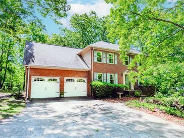 Charming two-story brick home featuring a spacious driveway and a two-car garage surrounded by lush trees at 1463 Shadowrock Hts, Marietta, GA 30062