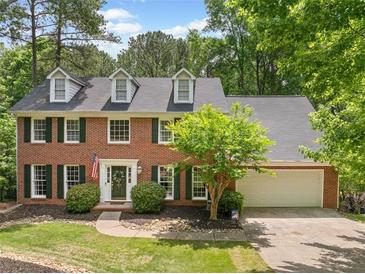 Charming brick two-story home with dormers, mature trees, dark shutters, and an attached two-car garage at 815 Lake Forest Pass, Roswell, GA 30076