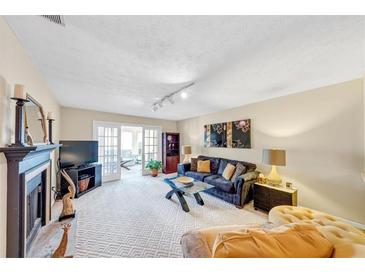 Bright living room featuring a fireplace, plush seating, and sliding doors leading to an outside living space at 4118 Stillwater Dr, Duluth, GA 30096