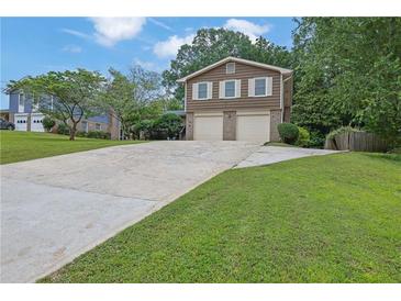 Charming two-story home with a two-car garage and expansive driveway on a verdant lot at 4457 Huntshire Dr, Stone Mountain, GA 30083