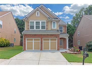 Charming two-story home featuring a brick and tan facade, a two-car garage, and a well-manicured lawn at 5645 Carrington Pl, Cumming, GA 30040