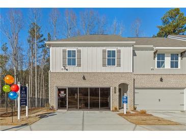 Charming two-story townhome featuring a brick facade, gray siding, and a convenient one-car garage at 4667 Larkfield Way, Powder Springs, GA 30127