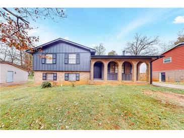 Charming brick home featuring a covered front porch with classic arched openings and well-maintained lawn at 8451 Magnolia Dr, Jonesboro, GA 30238