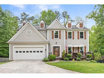 Charming two-story home with a manicured lawn, front porch, and attached garage, perfect for suburban living at 10090 Feather Sound Ct, Alpharetta, GA 30022