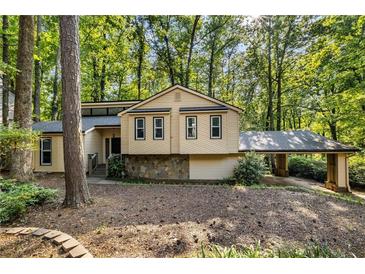 Charming home featuring a stone accent base, siding and covered parking, nestled among mature trees at 203 Concorde Sw Way, Lilburn, GA 30047