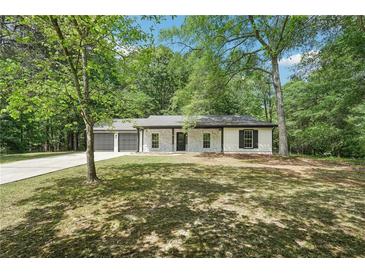 Charming single-story home with a manicured front yard and a two-car garage nestled among mature trees at 250 Huntcliff Ct, Fayetteville, GA 30214