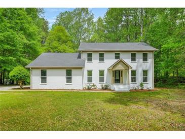 Charming two-story white brick home featuring a well-manicured lawn and mature trees at 230 Deer Forest Rd, Fayetteville, GA 30214
