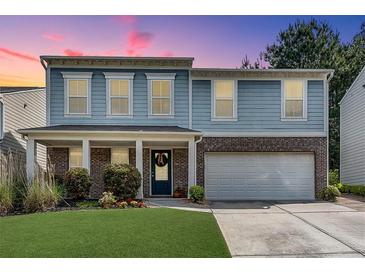 Charming two-story home features a two-car garage, manicured lawn and is beautifully landscaped at 5437 Blossom Brook Dr, Sugar Hill, GA 30518