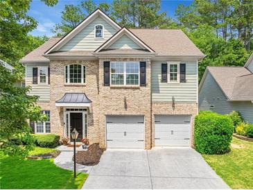 Charming two-story home with a brick facade and a two-car garage, surrounded by mature trees and landscaping at 525 Roland Manor Dr, Dacula, GA 30019