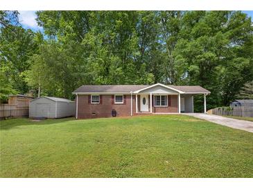 Charming brick home with a well-manicured lawn, convenient carport, and storage shed at 4781 Lincoln Ne Dr, Kennesaw, GA 30144