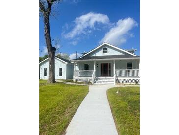 Charming light blue home with inviting front porch and well-maintained lawn on a beautiful day at 5191 Nw Emory Nw St, Covington, GA 30014