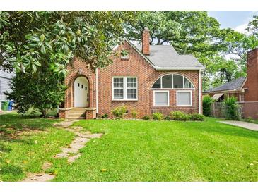 Charming brick home with a well-maintained lawn and arched doorway at 949 Hope Sw Dr, Atlanta, GA 30310