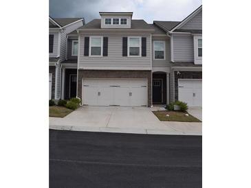 Charming townhome with a two-car garage, gray siding, and classic black shutters at 7624 Squire Ct, Fairburn, GA 30213