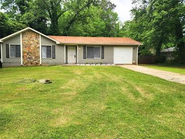 Charming one-story home with stone accents, a well-maintained lawn, and a private driveway at 8227 Englewood Trl, Riverdale, GA 30274