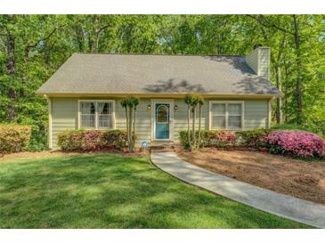Charming one-story home features a lush green lawn, mature landscaping, and a welcoming walkway to the front door at 3957 Woodland Cir, Conyers, GA 30013