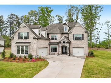 Elegant brick home boasts a two-car garage, lush lawn, and inviting landscaping at 6555 Hawkins Manor Dr, Cumming, GA 30040