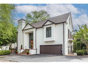 Elegant two-story home with white stucco exterior, brown trim, front-entry garage, and manicured landscaping at 1100 Parker Ne Pl, Atlanta, GA 30324