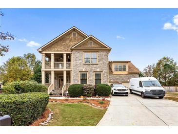 Charming two-story home with brick and siding, columns, landscaped yard, and a paved driveway at 1114 Ivey Chase Pl, Dacula, GA 30019
