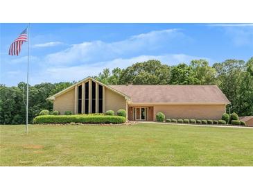 Spacious ranch-style home with manicured lawn, lush landscaping, and an American flag waving in front at 1724 Arbor Hill Rd, Canton, GA 30115