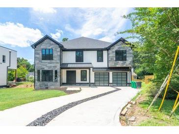Exterior facade of a large 2 story home with stone and white wood accents and a three car garage at 2740 Drew Valley Ne Rd, Brookhaven, GA 30319