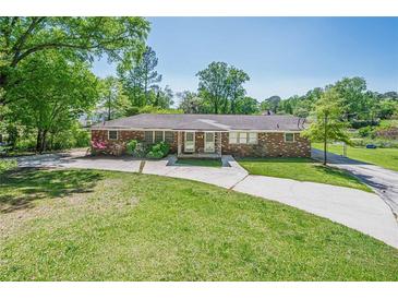 Ranch-style brick home boasts a spacious front yard and charming curb appeal with a long driveway on a sunny day at 3710 A B Lynn Dr, Powder Springs, GA 30127