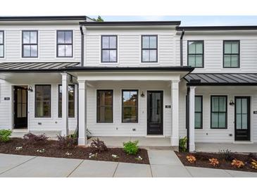 Charming townhomes featuring a white facade, black trim, covered entryway and landscaped front yard at 18 Black Gum Ln # 53, Auburn, GA 30011