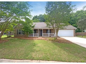 Charming single-story home with a brick facade, manicured lawn and attached two-car garage and front porch at 2012 Elm Grove Ln, Hampton, GA 30228