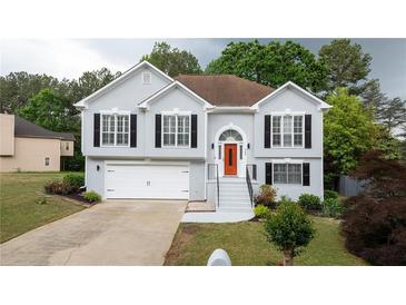 Charming two-story home featuring an attached garage, neatly landscaped yard and a bright orange front door at 440 Hickory Glen Sw Ln, Atlanta, GA 30311