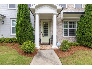 Charming entrance with columns, sage-colored door, and meticulous landscaping, creating a warm curb appeal at 10200 Windalier Way, Roswell, GA 30076