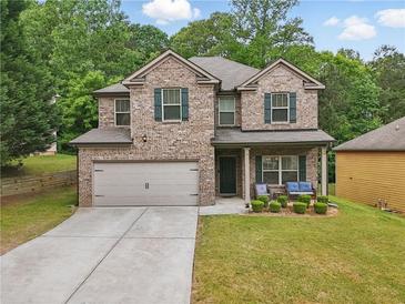 Charming two-story brick home with a well-manicured lawn and a cozy front porch seating area at 11028 Southwood Dr, Hampton, GA 30228