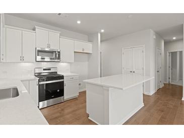 Modern kitchen features white cabinets, stainless steel appliances, and a central island at 488 Village Ln, Fairburn, GA 30213