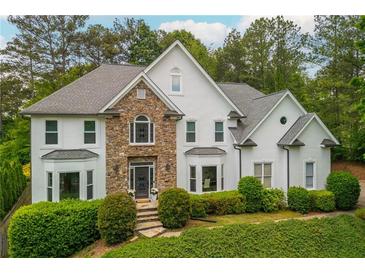 Stunning two-story home with a stone facade, arched window, lush landscaping, and an inviting entrance at 725 Eider Down Ct, Alpharetta, GA 30022