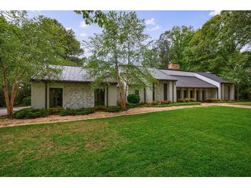 Charming single-story home with stone facade, metal roof and lush green lawn at 5120 Jett Forest Trl, Atlanta, GA 30327