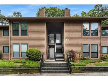 Inviting condo exterior featuring well-maintained landscaping and a two-story entrance with natural wood siding at 605 Parkaire Xing, Marietta, GA 30068