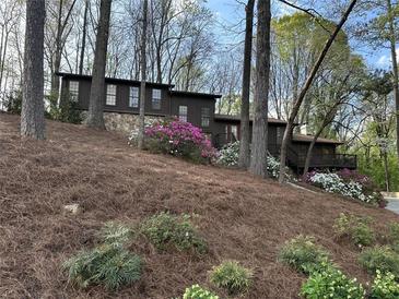 Charming brown home with stone base and colorful flower landscaping on a wooded lot at 475 Nottingham Dr, Marietta, GA 30066