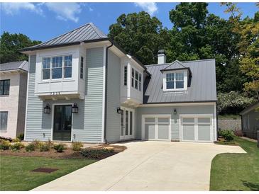 Charming two-story home featuring a metal roof, light blue siding, a two-car garage and a manicured lawn at 7235 Cordery Rd, Cumming, GA 30040