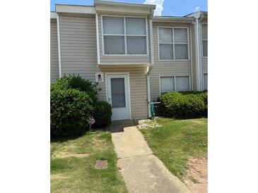 Tan siding townhouse with a well-manicured lawn and clean walkway leading to the front door at 102 Governors Dr, Forest Park, GA 30297