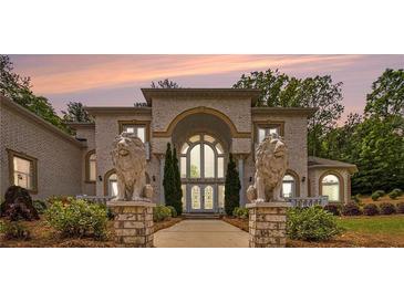 Stunning brick home with prominent lion statues, grand archway, and manicured landscaping at 2425 Wild Oak Ct, Stockbridge, GA 30281