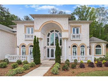 Stunning two-story brick home features a large arched entryway, lush landscaping, and decorative balustrades at 2425 Wild Oak Ct, Stockbridge, GA 30281