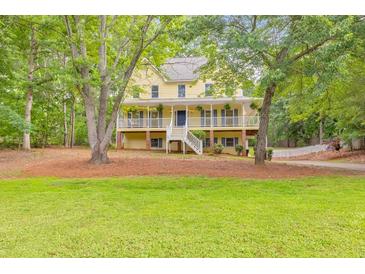 Charming yellow two-story home with a spacious front porch and well-manicured lawn surrounded by mature trees at 115 Eagle Ridge Dr, Canton, GA 30114