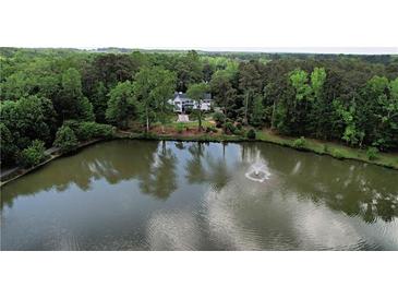 Picturesque aerial view of a lakeside home featuring lush greenery and a serene pond with a fountain at 3109 Country Lake Dr, Powder Springs, GA 30127