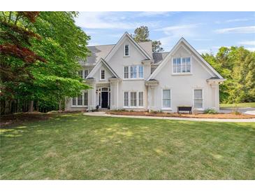 Elegant two-story home featuring a manicured lawn and classic architectural details and lush landscaping at 4585 Lakefield Bnd, Berkeley Lake, GA 30096