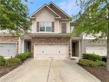 Charming townhome featuring a two-car garage, stone accents, and neutral siding at 7526 Stone Creek Path, Lithonia, GA 30038