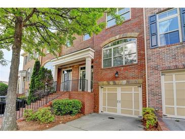 Charming brick townhome featuring an attached garage, a welcoming front porch and professional landscaping at 10898 Gallier St, Johns Creek, GA 30022