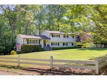 Charming two-story home with a lush green lawn, white fence, and mature trees creating a serene setting at 3519 Sunderland Ne Way, Brookhaven, GA 30319