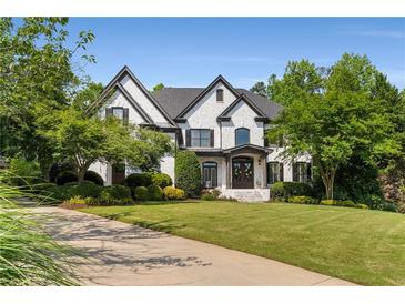 Striking two-story home showcasing a brick exterior, manicured lawn and professional landscaping at 12815 Oak Falls Dr, Alpharetta, GA 30009