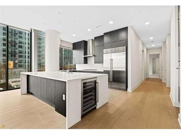 Modern kitchen with stainless steel appliances, island with wine cooler, and large windows with city views at 40 12Th St # 1006, Atlanta, GA 30309