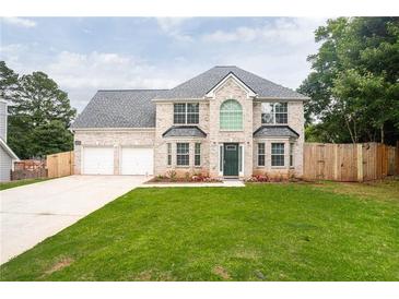 Charming two-story home with a well-manicured lawn, brick facade, and a two-car garage at 1976 Glen Echo Dr, Decatur, GA 30032